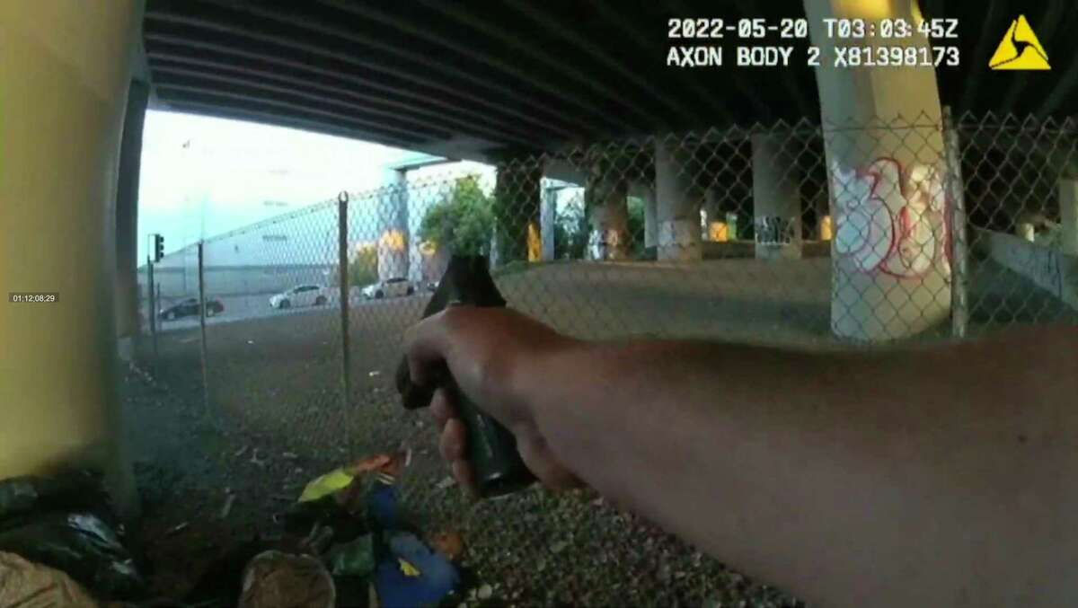 A San Francisco police officer points a gun at two men fighting on the ground on May 19 near Mission Bay in an image from a body-worn camera.