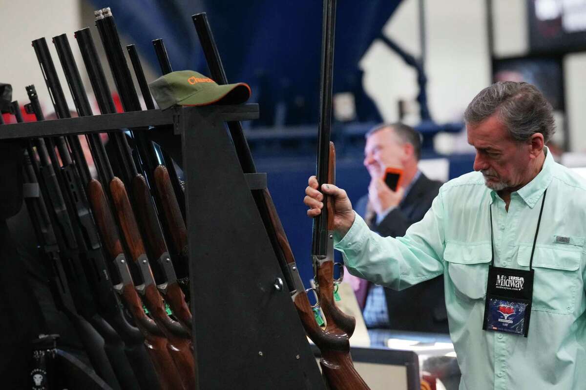 Attendees browse through weapons displayed on the show floor during the 2022 Annual Meetings and Exhibits at the George R. Brown Convention Center Friday, May 27, 2022 in Houston.