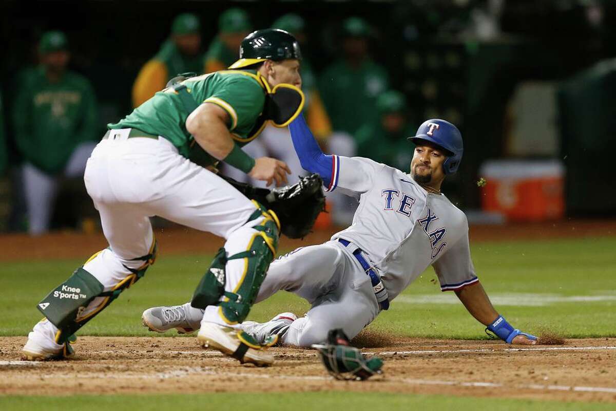 OAKLAND, CALIFORNIA - MAY 27: Marcus Semien #2 of the Texas Rangers slides in safe at home plate to score on a double by Adolis Garcia #53 in the top of the eighth inning against the Oakland Athletics at RingCentral Coliseum on May 27, 2022 in Oakland, California. (Photo by Lachlan Cunningham/Getty Images)