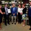 Chair of the Board of the Darien Chamber of Commerce, Cheryl Williams, presents a plaque to Greg Palmer, Al Palmer, Megan Palmer Rivera, Cindy Palmer Dean, and Travis Dean, to celebrate the 100th anniversary of Palmer's Market Wednesday, June 9, 2021, in Darien, Conn.