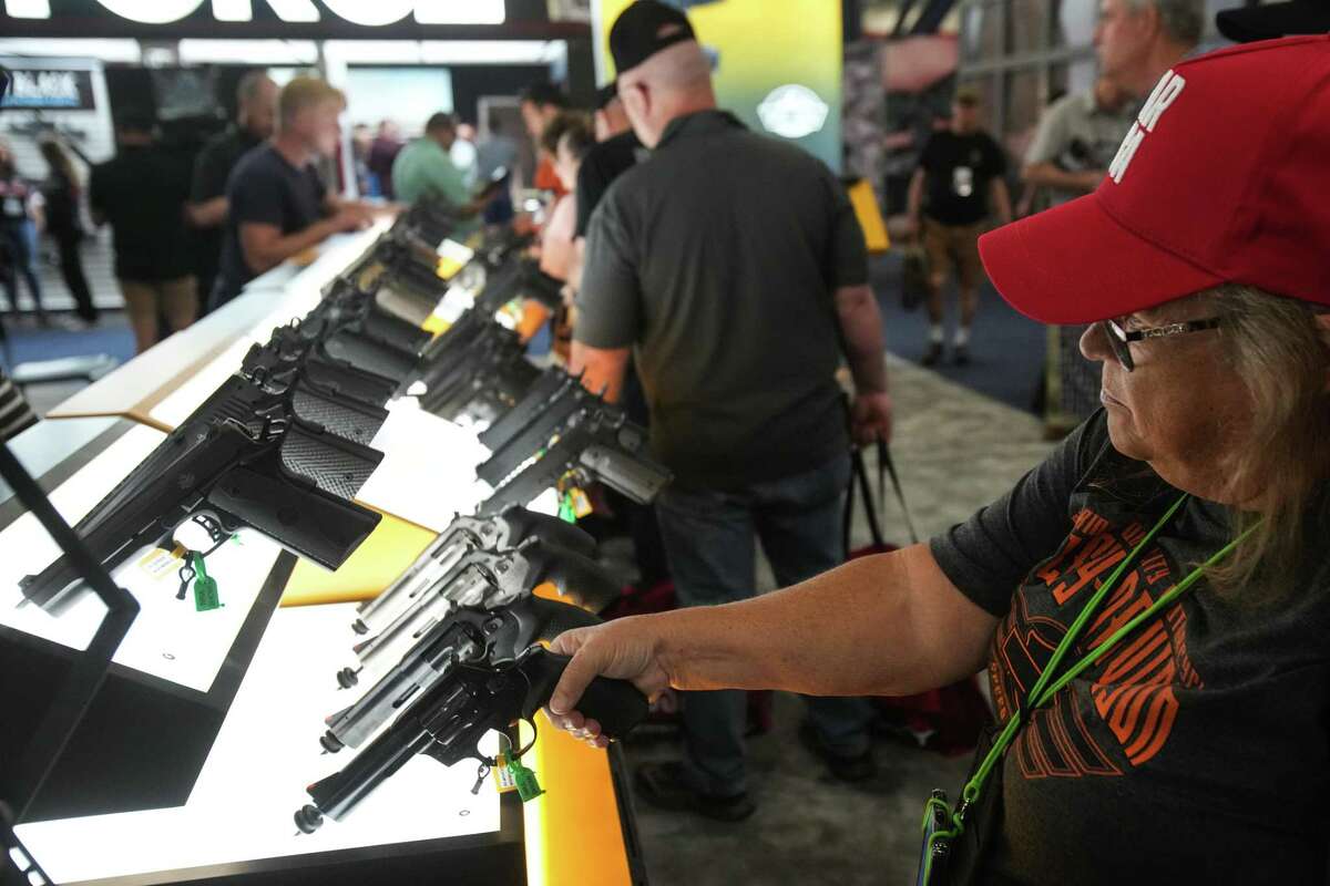 NRA convention attendees browse weapons displayed on the show floor Friday at Houston’s George R. Brown Convention Center.