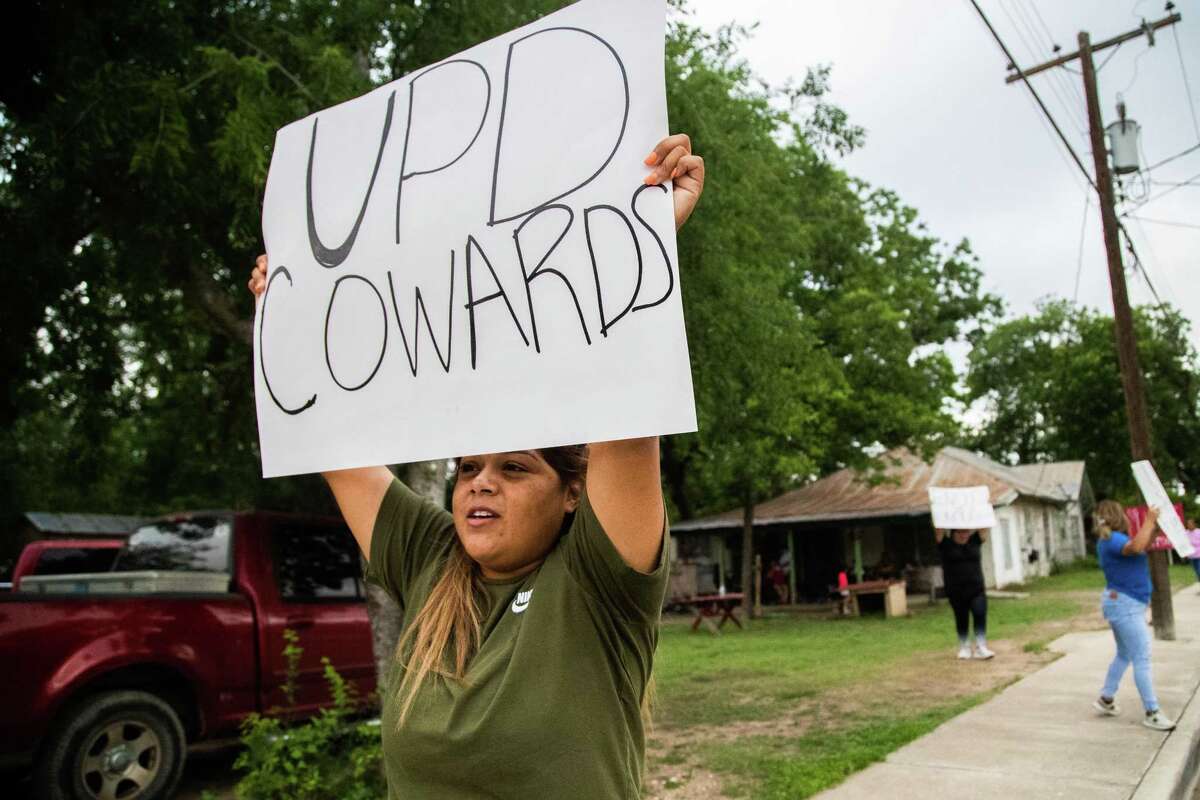 Jennifer Morales, 29, stand on the edge of her grandmother’s home in Uvalde with a sign that reads “UPD Cowards’” Sunday, May 29, 2022. UPD refers to the Uvalde Police Department, which is currently a department under scrutiny for their response to the school mass shooting that killed 21 people.
