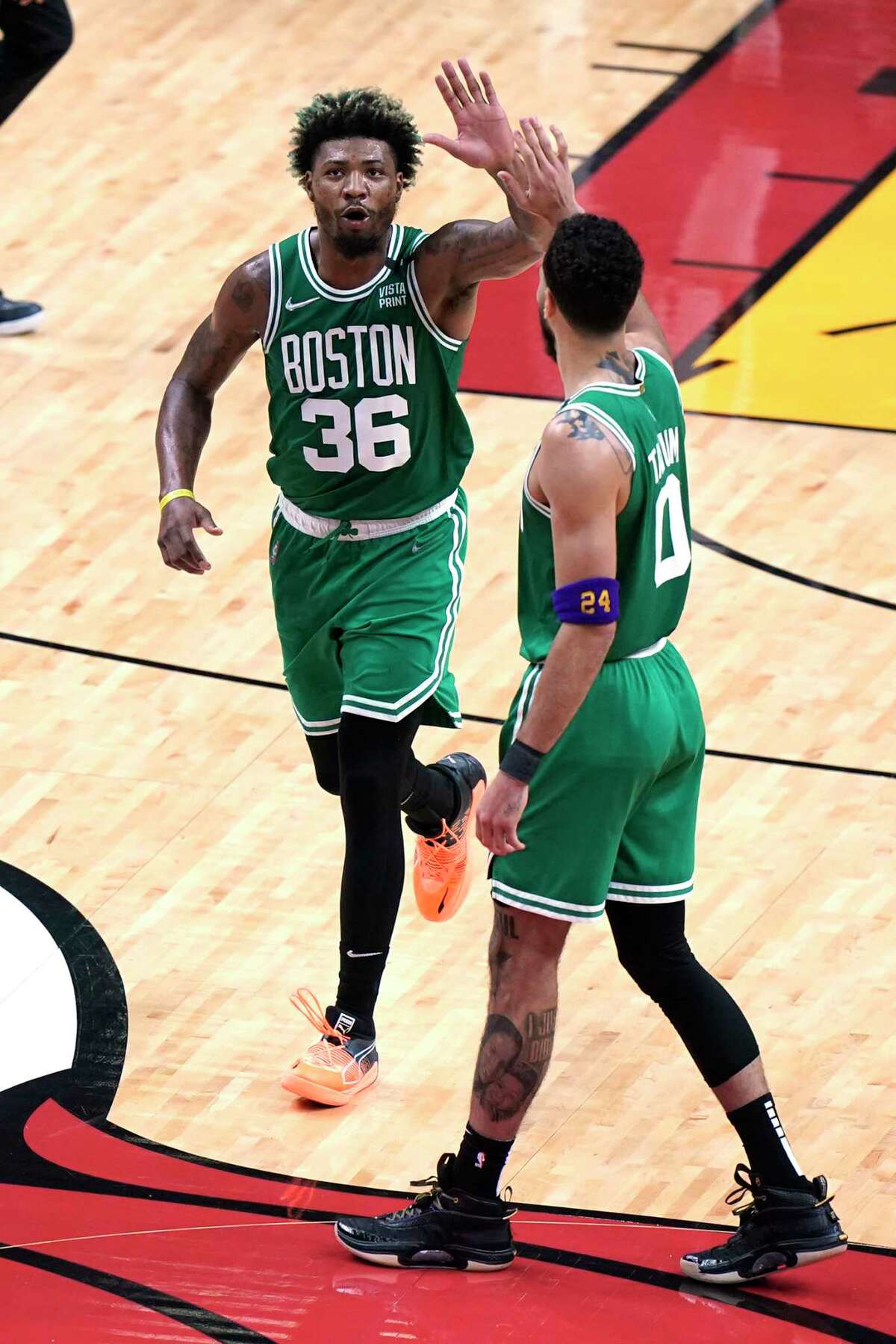Boston Celtics guard Marcus Smart (36) and forward Jayson Tatum (0) celebrate after scoring during the first half of Game 7 of the NBA basketball Eastern Conference finals playoff series against the Miami Heat, Sunday, May 29, 2022, in Miami.