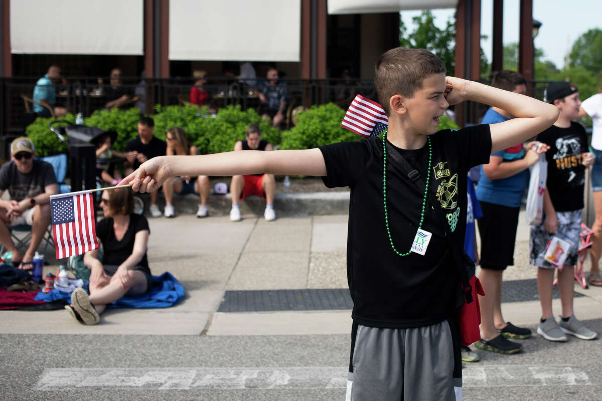 Carson Luft, 11, holds two American flags while pretending to direct traffic during a Memorial Day parade Monday, May 30, 2022.