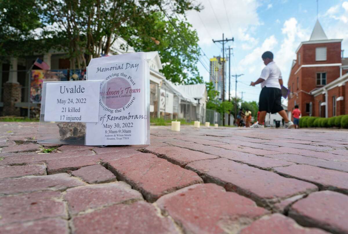 Volunteers pick up candles representing victims of mass shootings following a ceremony and vigil at the intersection of Andrews and Wilson streets among the bricks of Freedmen’s Town on Monday morning, May 30, 2022, in Houston.
