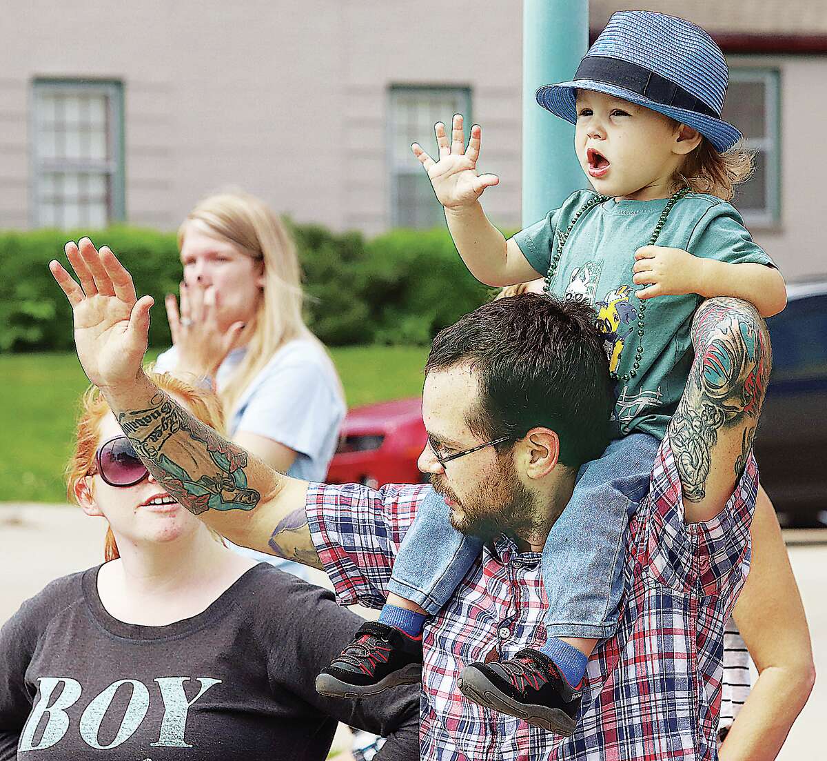 John Badman|The Telegraph Osias Tindall, 2, waves at passing entries in the Memorial Day Parade Monday as he sits on the shoulders of his dad, Kevin Tindall, of Godfrey.
