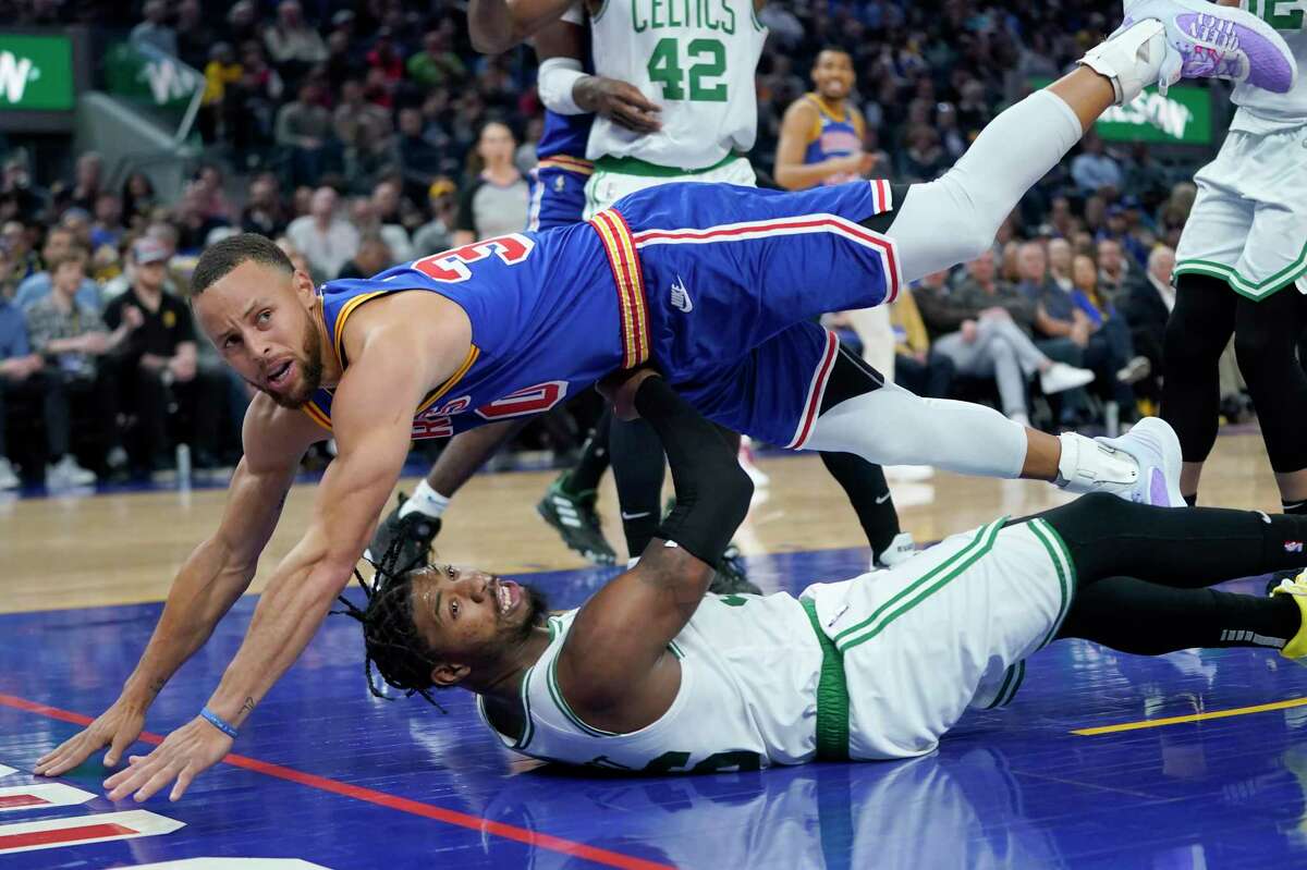 Golden State Warriors guard Stephen Curry, top, falls over Boston Celtics guard Marcus Smart during an NBA basketball game in San Francisco, Wednesday, March 16, 2022. (AP Photo/Jeff Chiu)
