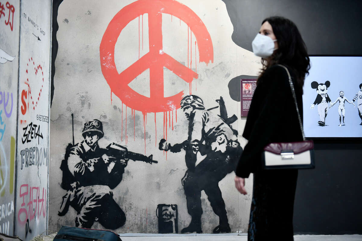 A woman looks at a Banksy artwork during the "The World of Banksy" Art Exhibition at Porta Nuova Railway Station on February 24, 2022 in Turin, Italy. (Photo by Stefano Guidi/Getty Images)
