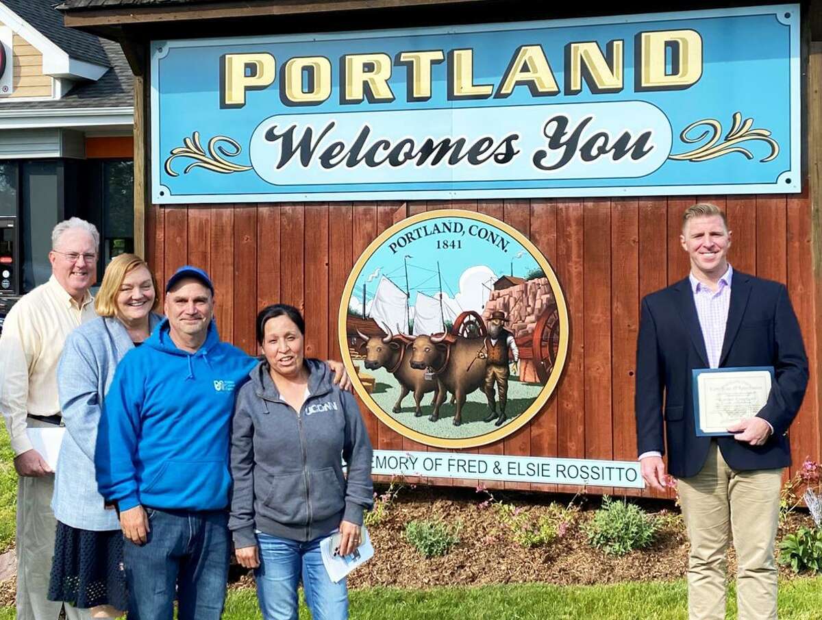 The Portland Historical Society has restored the Portland welcome sign by the Arrigoni Bridge. From left are trustee Chairman Bob McDougall, society President Julie Macksoud, property owners Mike and Patricia Ruffino, and First Selectman Ryan Curley, who accepted the gift on behalf of the community.
