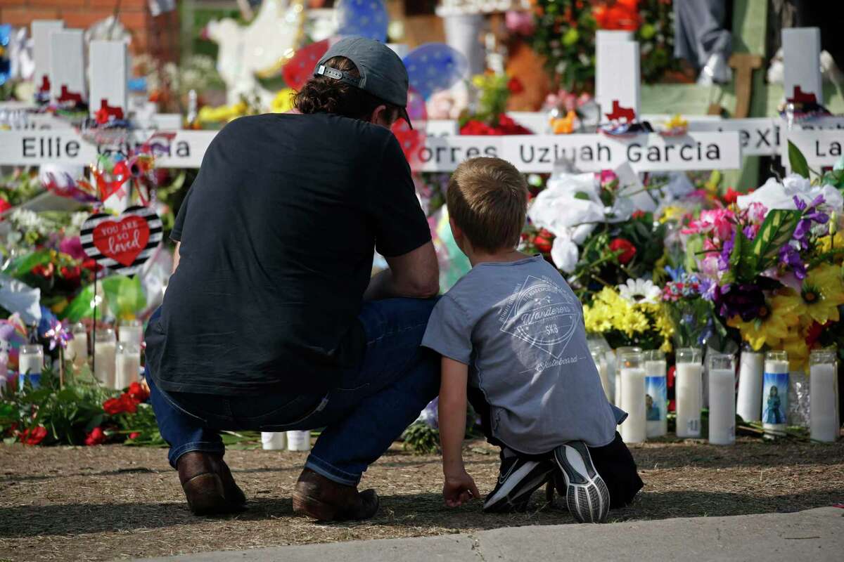 A man and a child pay their respects at a memorial outside Robb Elementary School Sunday. We’ve come to expect nothing from our elected leaders to prevent gun violence, and we have to demand more.