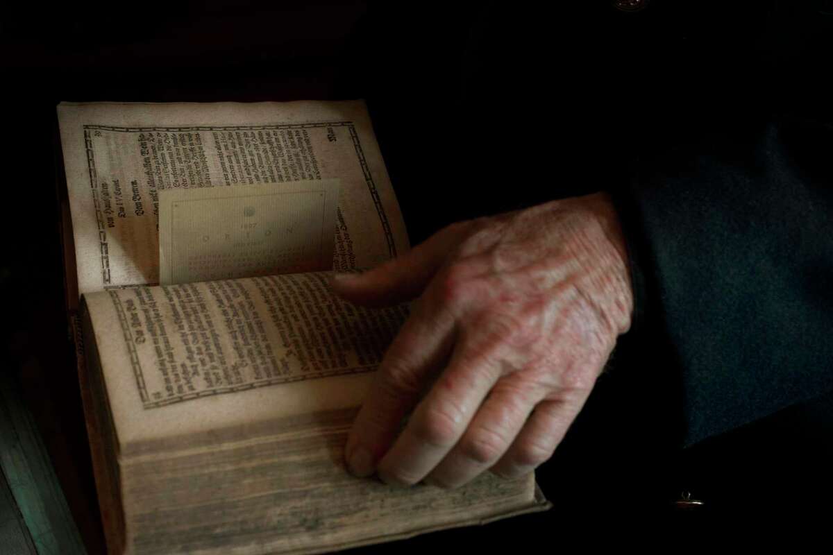 肖恩·萨克雷(Sean Thackrey)在家中的图书馆里，手里拿着他心爱的物品之一:约翰·科勒(Johann Coler)写的一本17世纪的德国酿酒书。