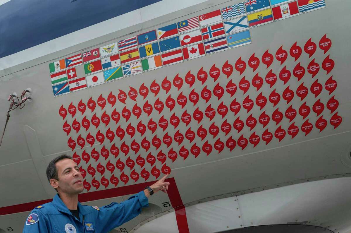 Lt. Commander Sam Urato, a P-3 pilot of National Oceanic and Atmospheric Administration, points to decals on the fuselage of the Lockheed WP-3D Orion 'hurricane hunter' aircraft representing the hurricanes it has penetrated during a hurricane awareness tour at Washington National Airport, Arlington, Va., Tuesday, May 3, 2022. Hurricane season starts Wednesday, June 1, 2022, and it's looking busy because every factor out there is pointing to another nasty year in the Atlantic.