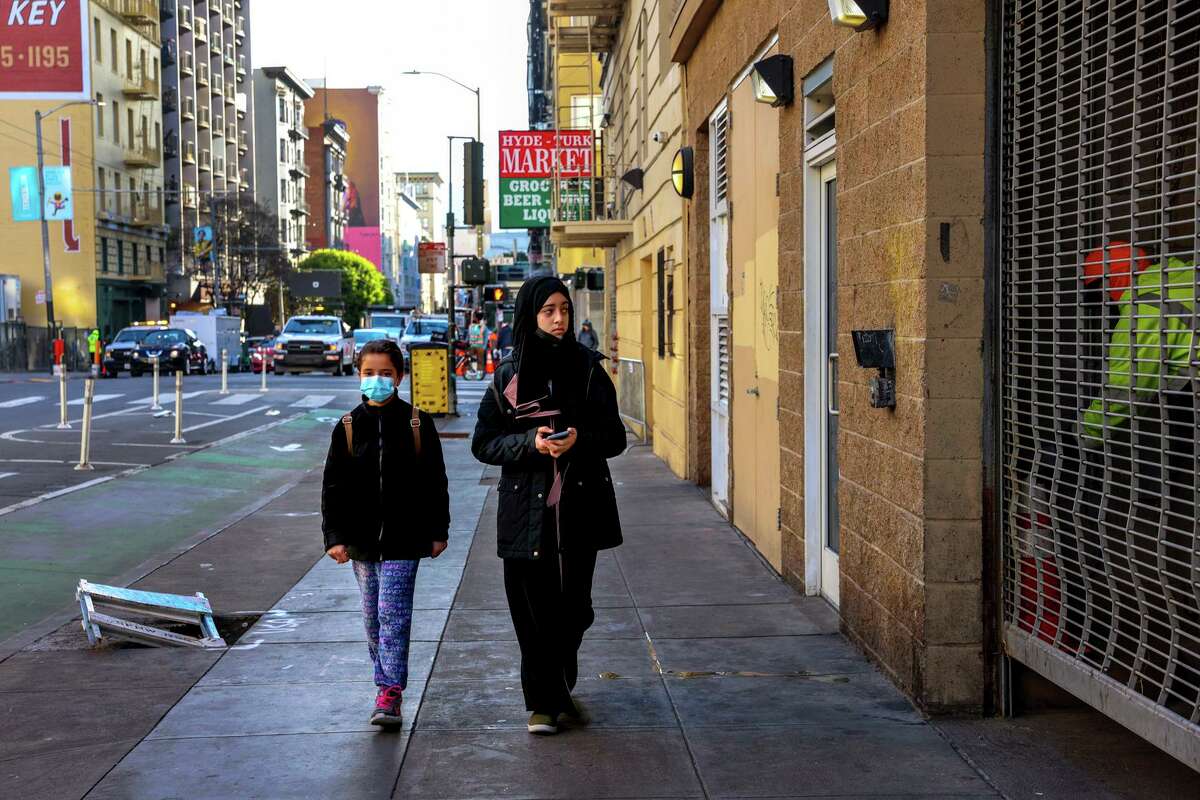 Raghad Saleh, 12, right, walks her sister Maya Saleh, 10, to school on Friday, February 25, 2022, in San Francisco, Calif. Raghad was stuck in Egypt in 2020 when her family moved to San Francisco from Yemen due to Visa problems. She was attacked by a stranger last year on her walk to school.