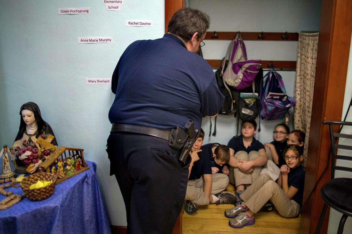 FILE — New Washington, Ohio, Chief of Police Scott Robertson talks with fourth grade students as they huddle in closet a during a lockdown drill at the St. Bernard School in New Washington, Ohio, Jan. 14, 2013. The shooting massacre at a Texas elementary school has spurred renewed calls for school safety, but experts debate whether more heavily fortified schools are the right solution. (AP Photo/Craig Ruttle, File)