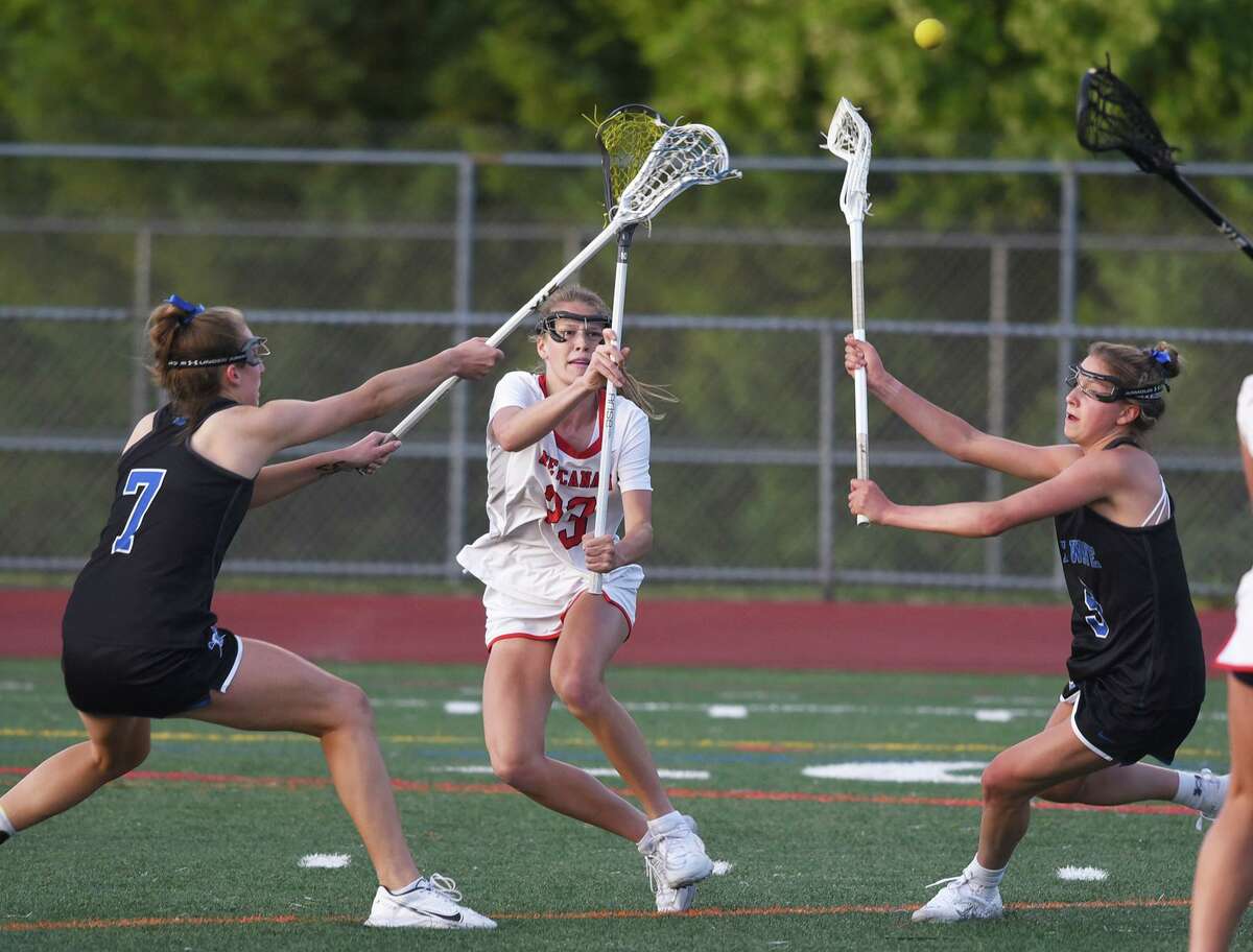 New Canaan’s Lexie Tully (23) sends a pass through traffic during the FCIAC girls lacrosse final in Norwalk on May 25.