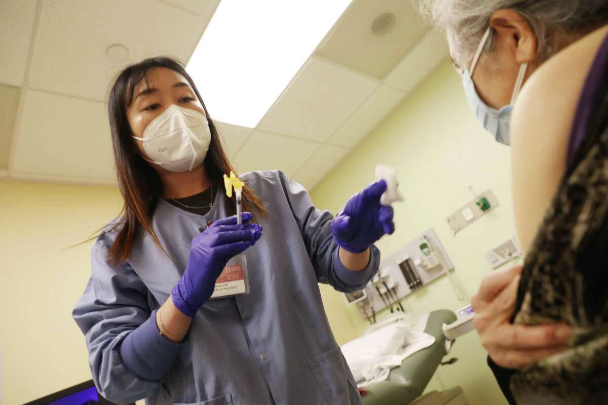 Medical assistant Yinhua Cui prepares to give a COVID booster shot to a patient at Chinese Hospital in San Francisco on June 1. Coronavirus cases are continuing to fall or level off across the Bay Area as the spring surge dies down.