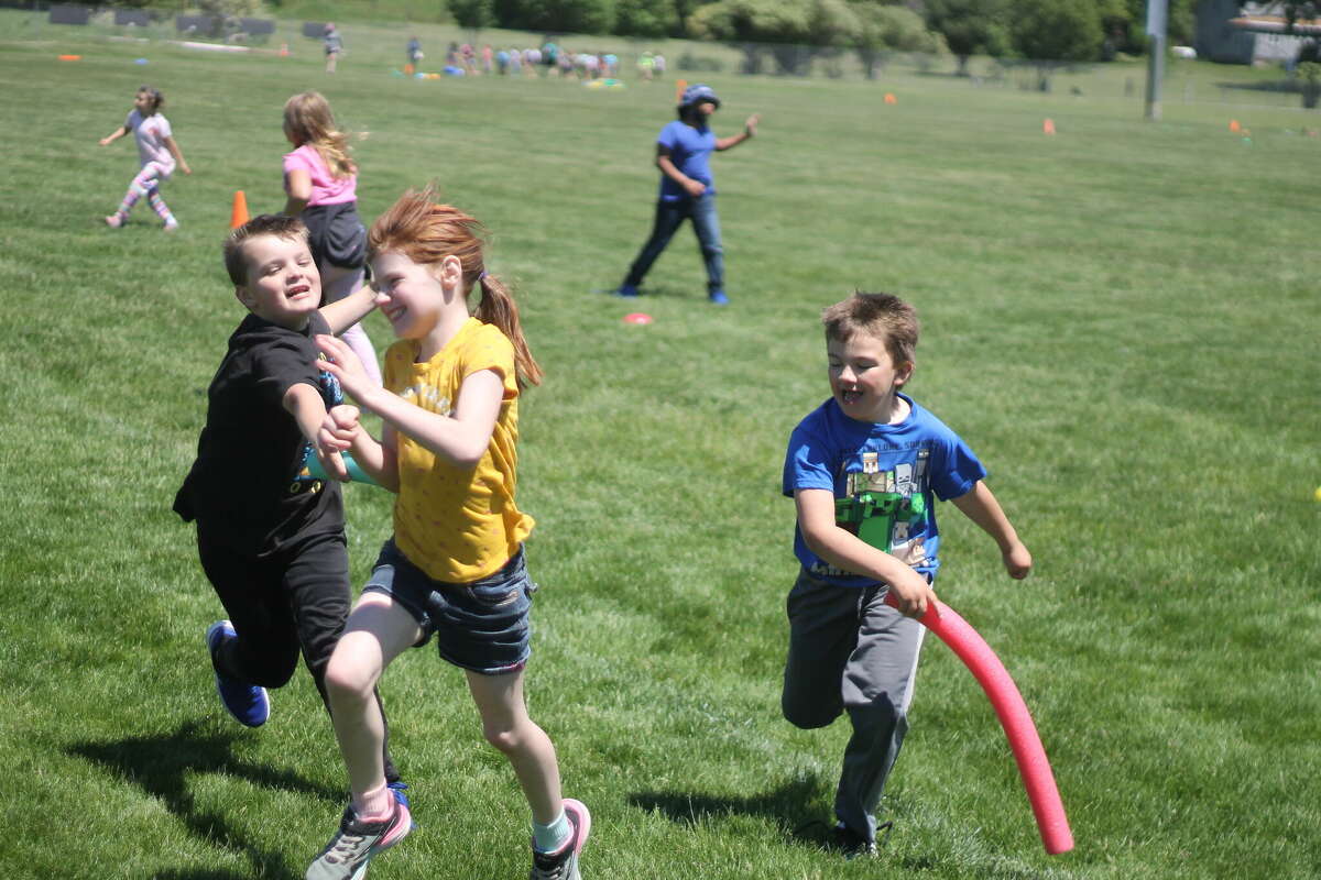 Second grade students play a game of tag Thursday on Chippewa Field during Manistee Area Public Schools' field day event.