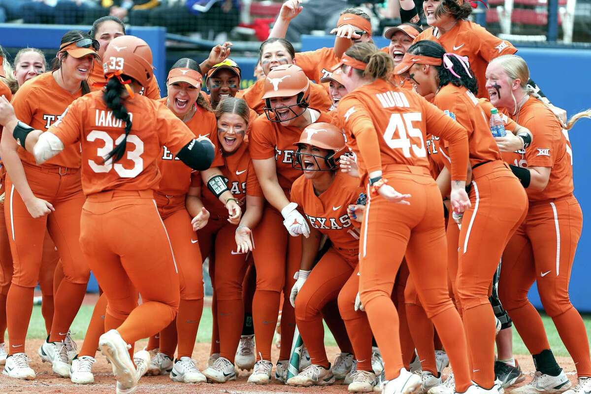 Texas catcher Mary Iakopo (33) is greeted by her team at home plate after hitting a home run in the third inning of an NCAA softball Women's College World Series game against UCLA on Thursday, June 2, 2022, in Oklahoma City. (AP Photo/Alonzo Adams)