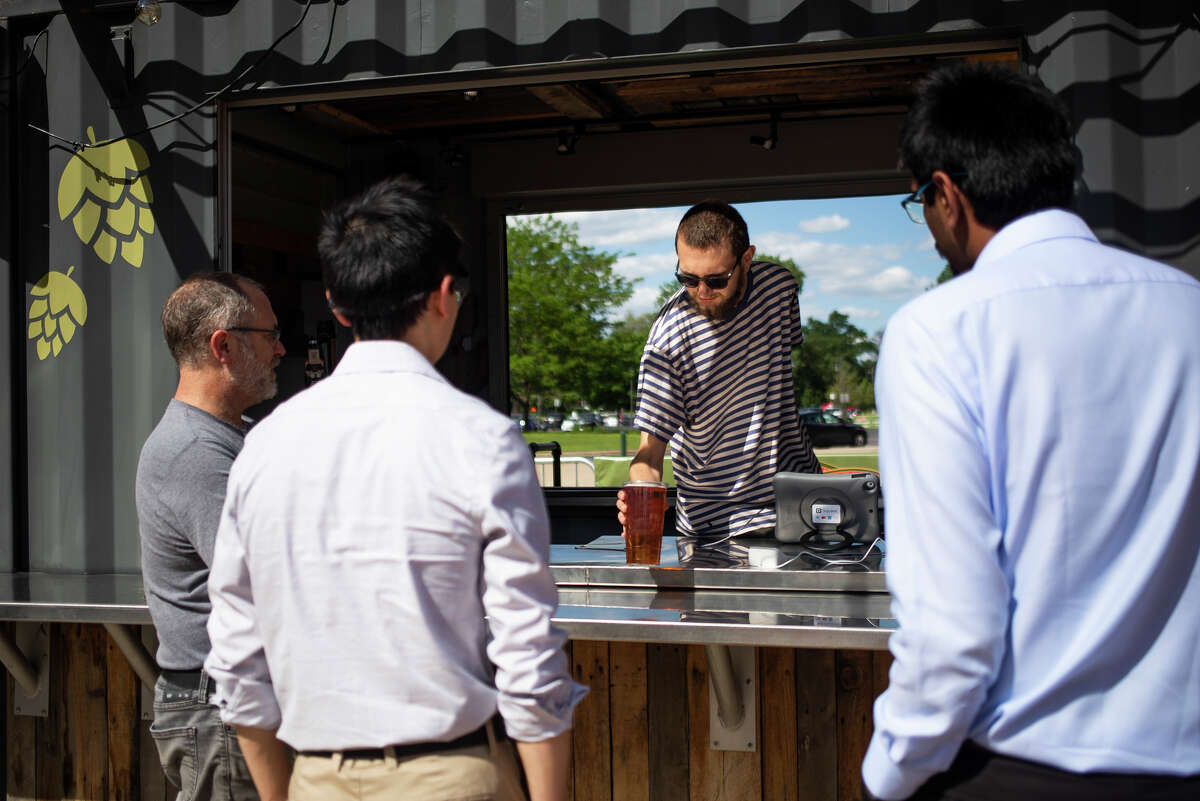 Lucas Tews, center, serves a cup of beer to a group of customers during opening day of the season for Larkin Beer Garden Thursday, June 2, 2022 at Dow Diamond.