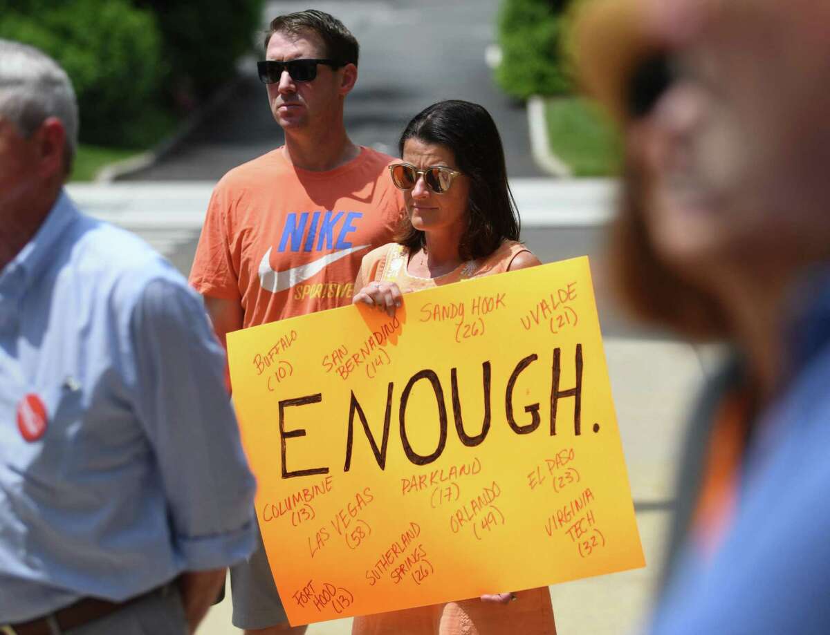Greenwich residents Tom and Miriam Kreuzer hold a sign as First Selectman Fred Camillo makes a proclamation for National Gun Violence Awareness Day outside Town Hall in Greenwich, Conn. Thursday, June 2, 2022. The proclamation states that "The Town of Greenwich and its leadership is committed to protecting the rights of its citizens while remembering the lives lost from senseless gun violence."