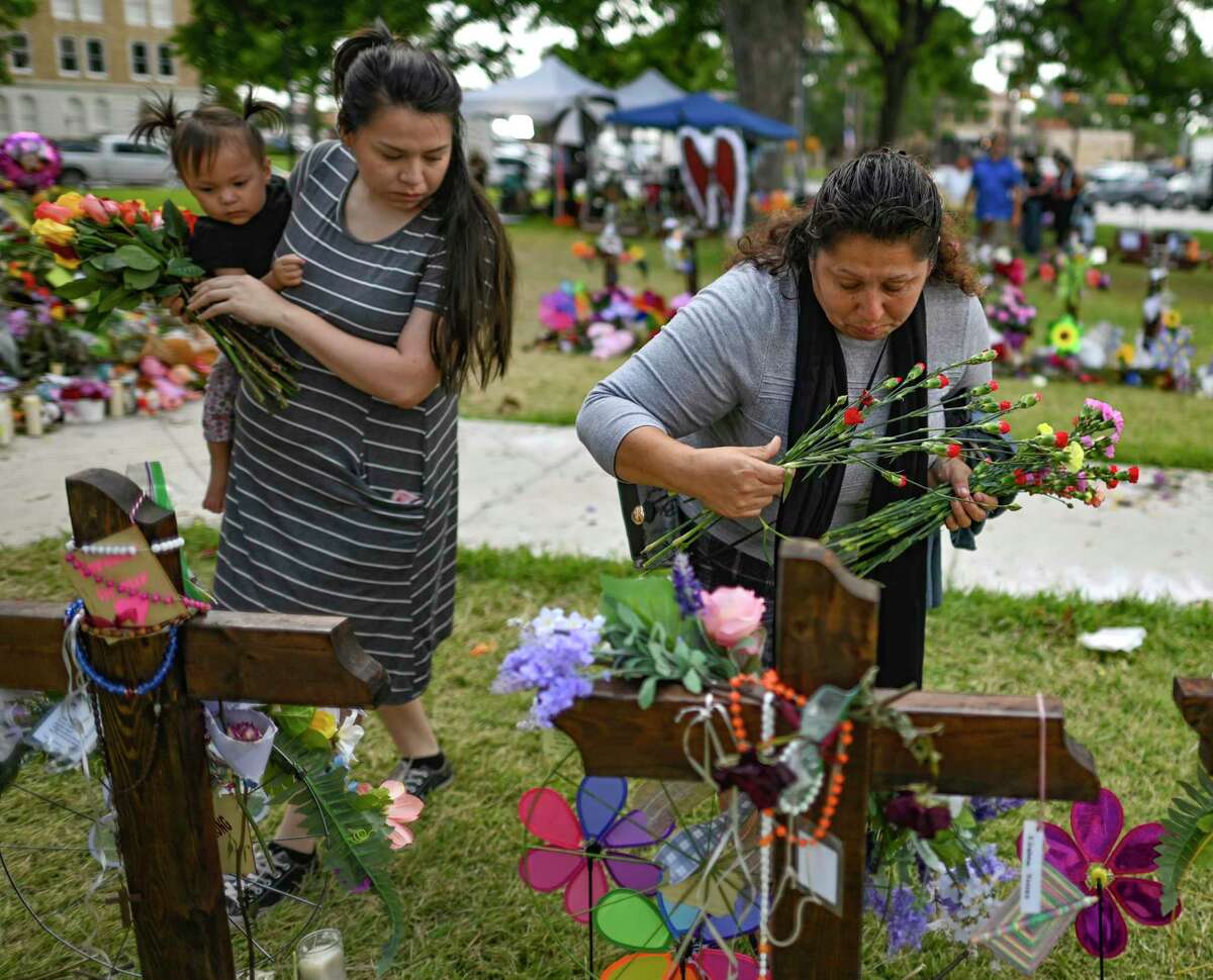 Neva Ramirez, right, and her daughter, Rita Garcia, and granddaughter, Iliana, place flowers at crosses in the main plaza in Uvalde, Texas, on Thursday, June 2, 2022. A gunman shot and killed 19 students and two teachers last week at Robb Elementary School.