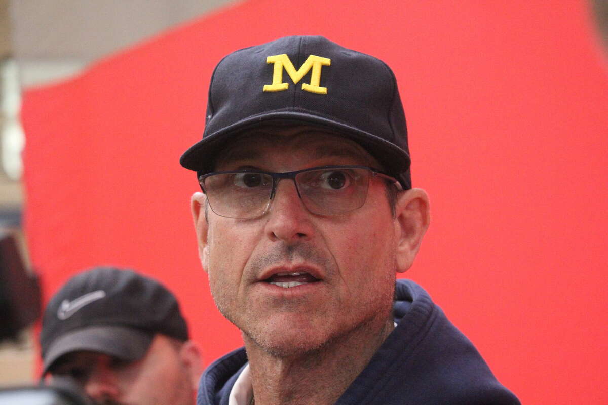 Michigan coach Jim Harbaugh answers questions from reporters inside the Ferris student rec center on Thursday while attending the prep showcase.