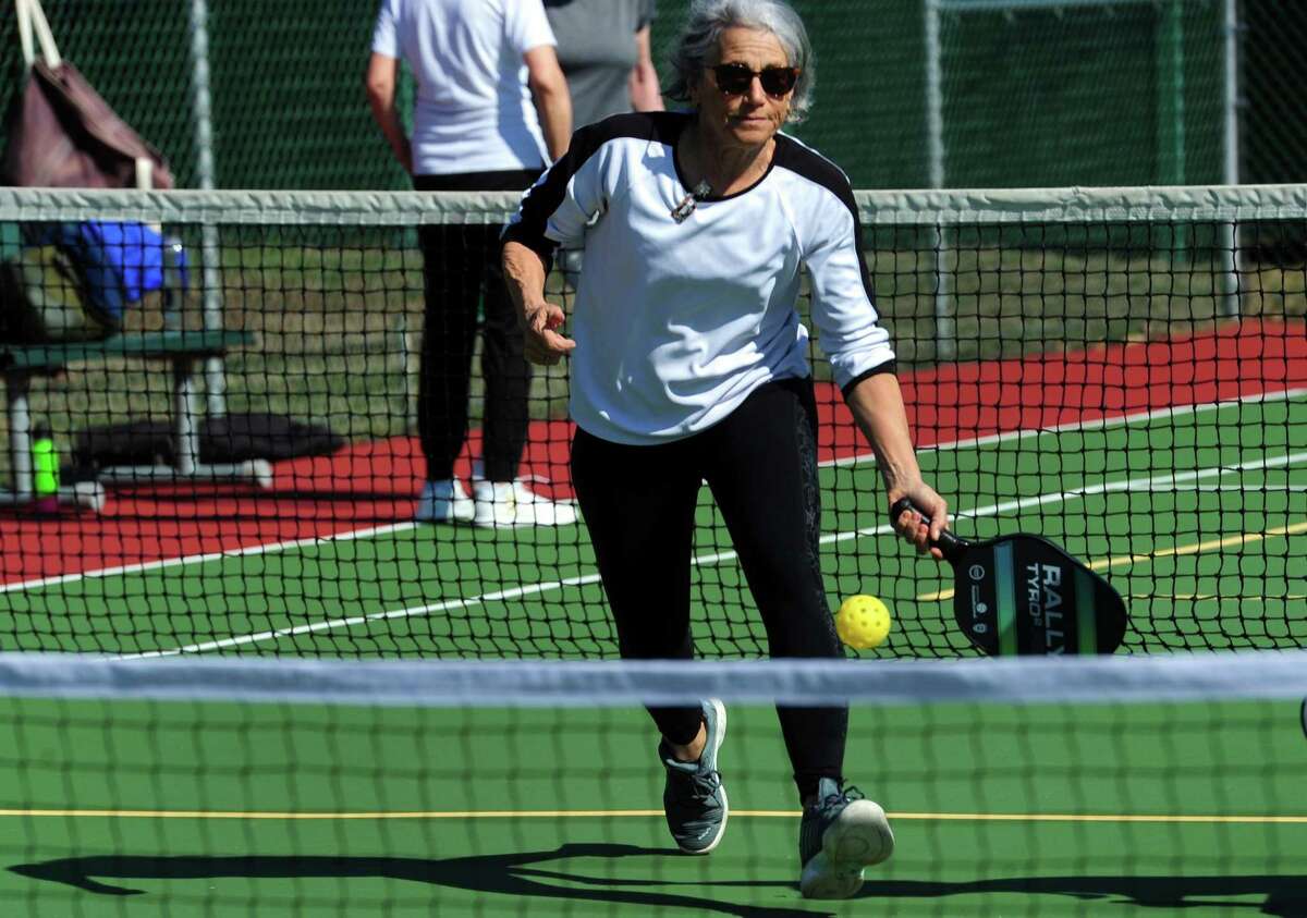 Gwenn Herz returns the ball during a game of pickleball on the tennis courts at Loughlin Avenue Park in Greenwich, Conn., on Friday March 18, 2022. Pickleball, a sport gaining in popularity in the town, has plenty of residents seeking the limited public court space that is available, creating heavy demand. Now, even after a recent budget cut, the search continues to create more court availability.