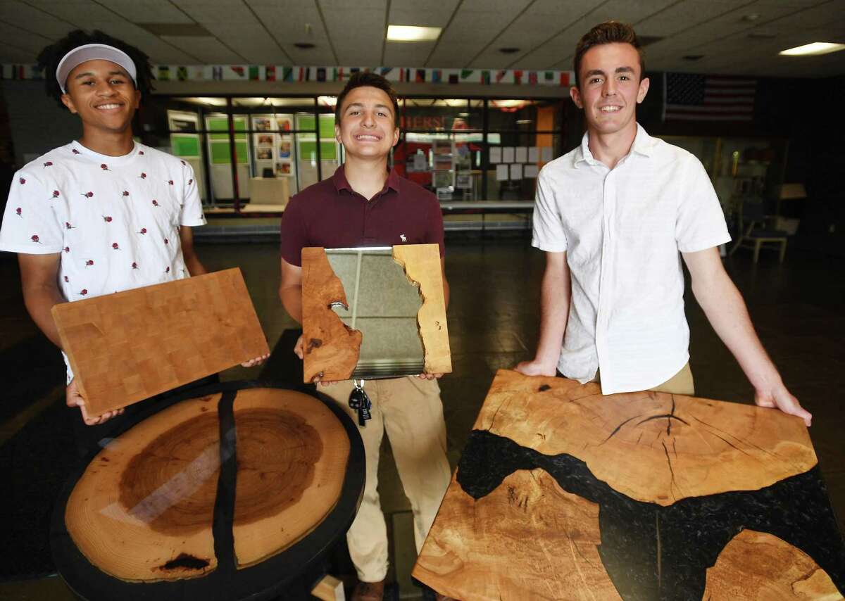 From left; carpentry students Dante Duarte, 16, of Hamden, Thomas Allen, 17, of Milford, and Dominic Smeraglino, 17, of Bridgeport, with furniture projects they constructed with materials recycled from the school at Platt Tech in Milford, Conn. on Wednesday, June 1, 2022. The items are being raffled off as a fundraiser.