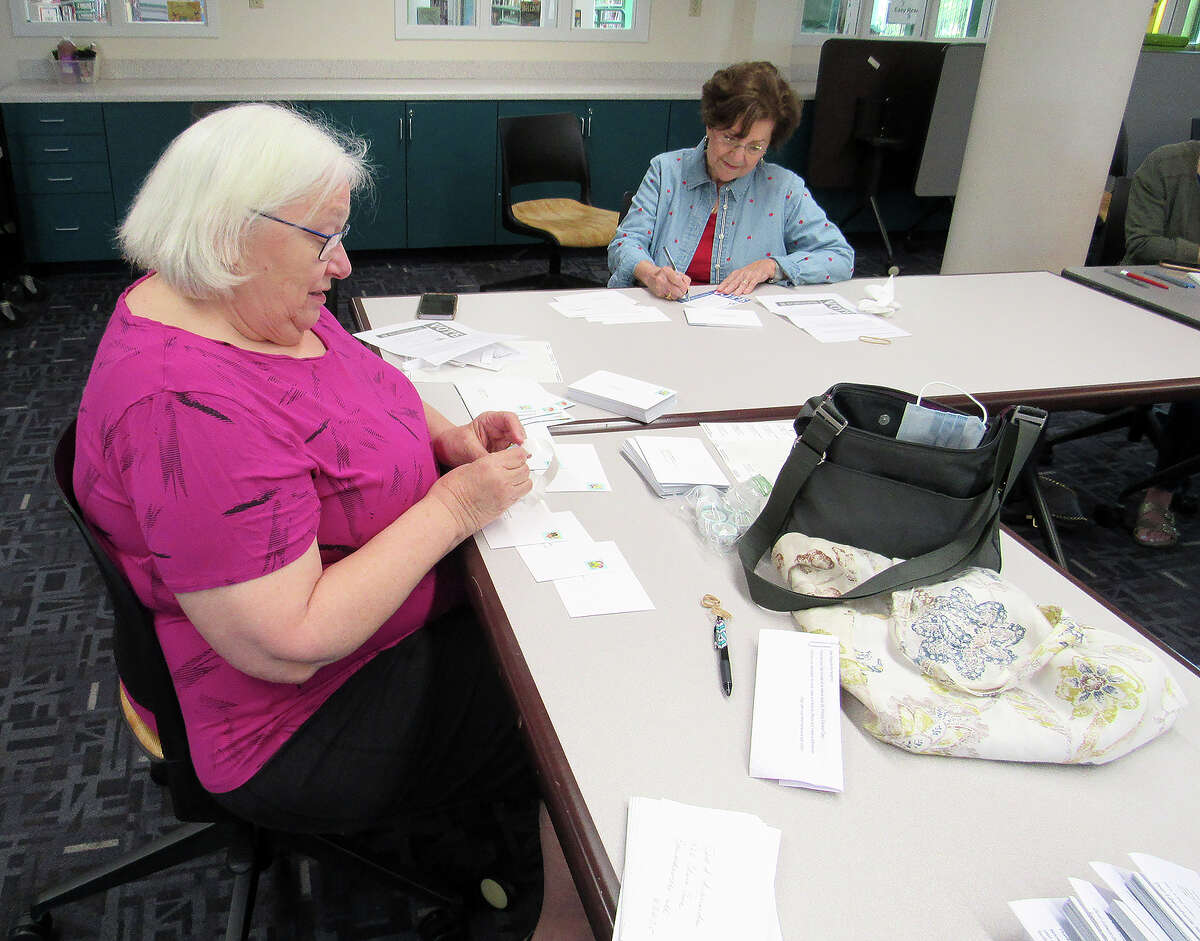 Carol Gerdt, left, and Anne Masters of the League of Women Voters of the Edwardsville Area write postcards to registered voters in a local precinct who did not vote in last spring's local election. The postcard campaign is an experiment to increase voter turnout.