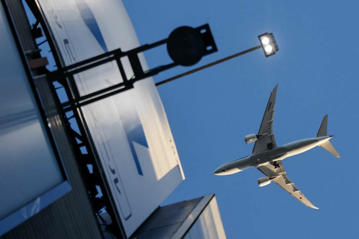 An airplane flies over a rooftop in the Shibuya district of Tokyo in August 2021.