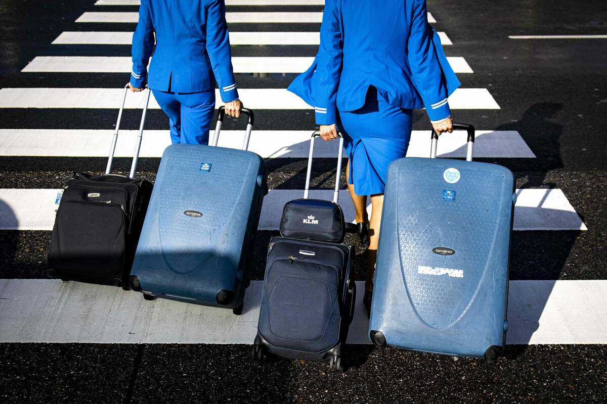 KLM flight attendants pull their trolley bags as they make their way to Amsterdam Schiphol Airport in May 2022.