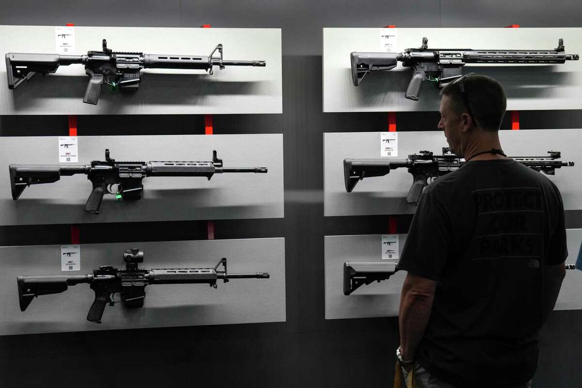 Attendees browse through weapons displayed on the show floor during the 2022 Annual Meetings and Exhibits at the George R. Brown Convention Center Friday, May 27, 2022 in Houston.