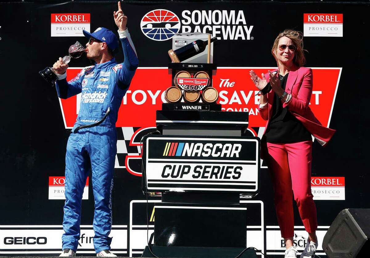Sonoma Raceway Executive Vice President and General Manager Jill Gregory applauds as Kyle Larson slugs wine after winning the 2021 Toyota/Save Mart 350.
