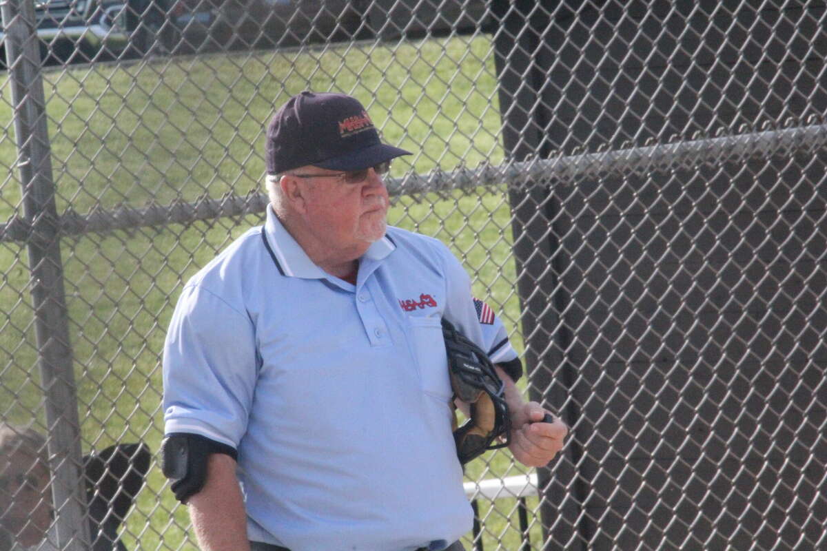 Former Chippewa Hills coach Jim Novar gets set to umpire the last inning of the last softball game of his career on Wednesday in Big Rapids.