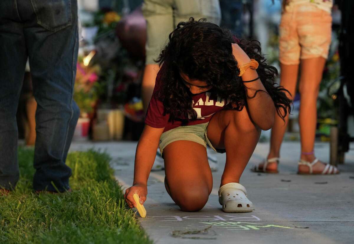 Genevieve Tijerina, 11, uses chalk to write “We Will Rise” on the ground at the Town Square, the site of a memorial for the victims of the mass shooting at Robb Elementary School, on Friday, May 27, 2022, in Uvalde, Texas.
