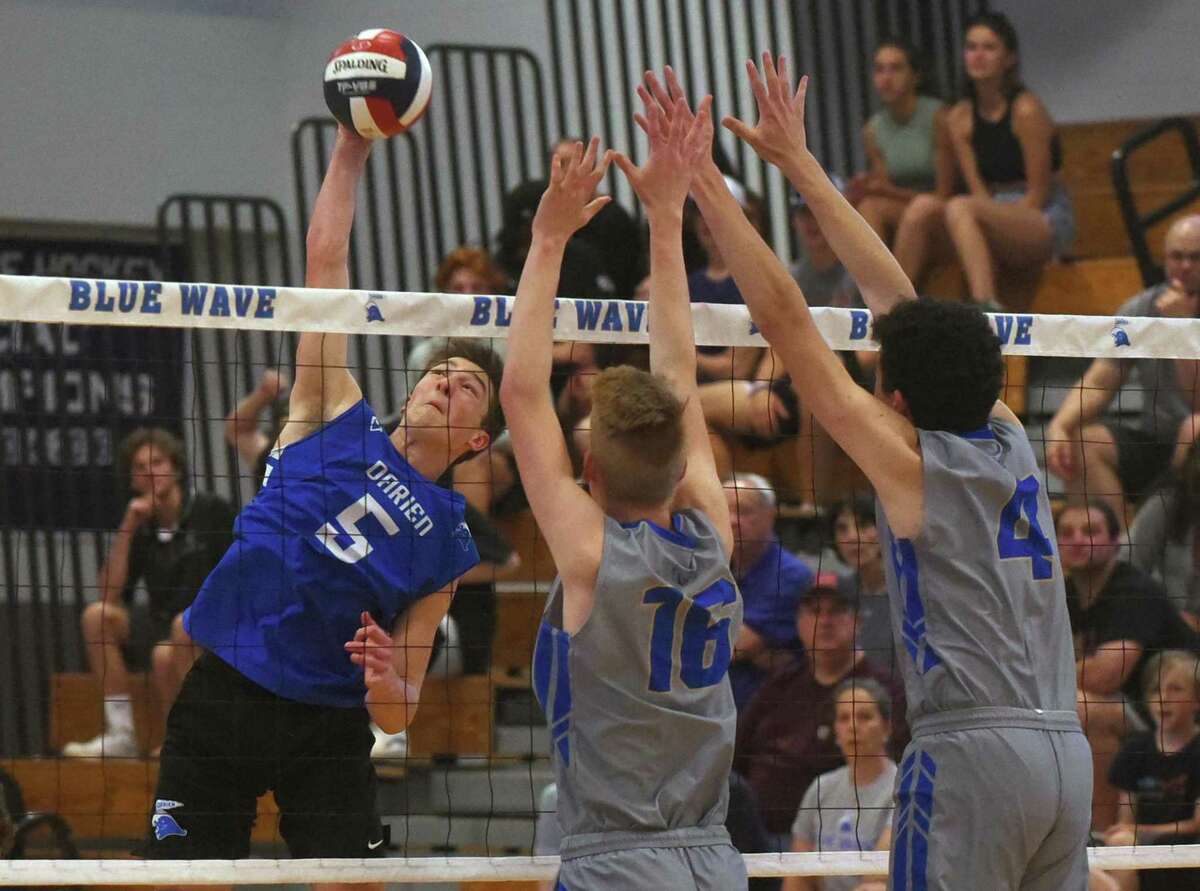 Darien's Luke Bradbury (5) takes a shot while Newtown's Henry Warner Bacon (16) and Matt Mattera (4) try to block during the Class L boys volleyball quarterfinals in Darien on Friday, June 3, 2022.