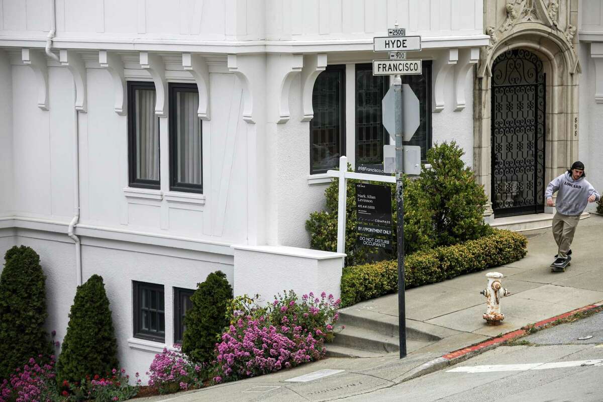 A skateboarder passes by a for sale sign on the corner of Hyde and Francisco streets in the Russian Hill neighborhood in San Francisco, Calif. on Wednesday, June 23, 2021.