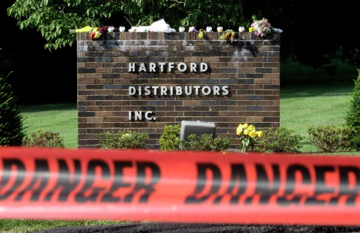 A sign at the entrance to Hartford Distributors, in Manchester, Conn., is seen behind warning tape, Thursday, Aug. 5, 2010. Eight people were killed Tuesday when Omar Thornton opened fire after a disciplinary hearing at the beer distributorship in Manchester, before killing himself. Flowers and candles rest on top of the sign.