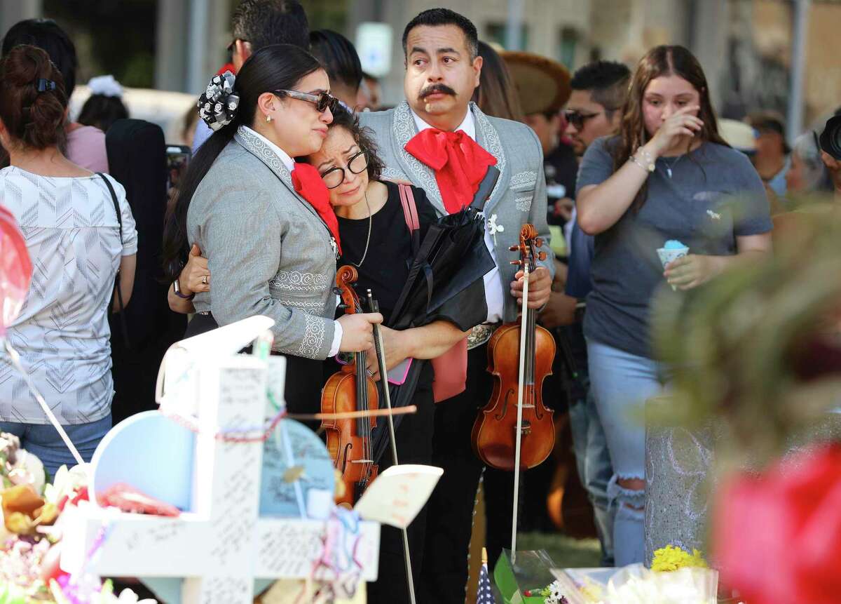 Mariachi performer Alejandra Guzman and her mother, Esmeralda, hug beside her father, Miguel (second from right) after they join a group of mariachis to play in the Uvalde Town Square on Wednesday, June 1, 2022.