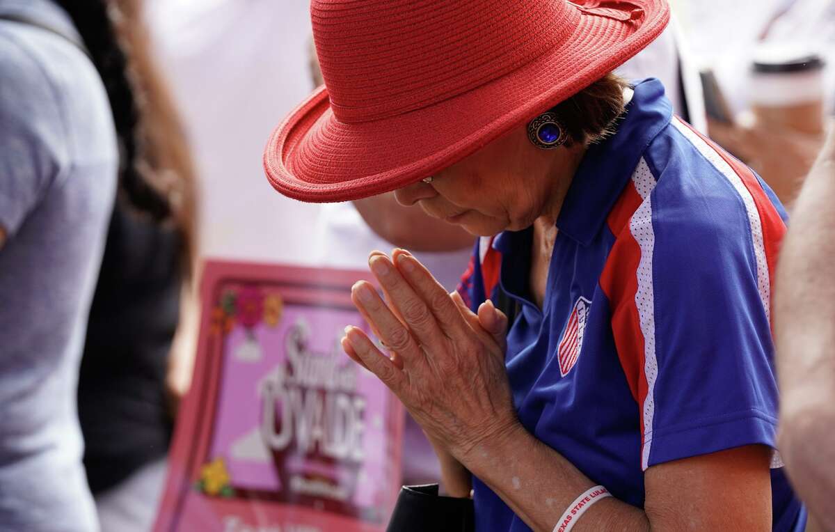 A woman prays during a “Stand with Uvalde” call-to-action rally Saturday morning in Travis Park.