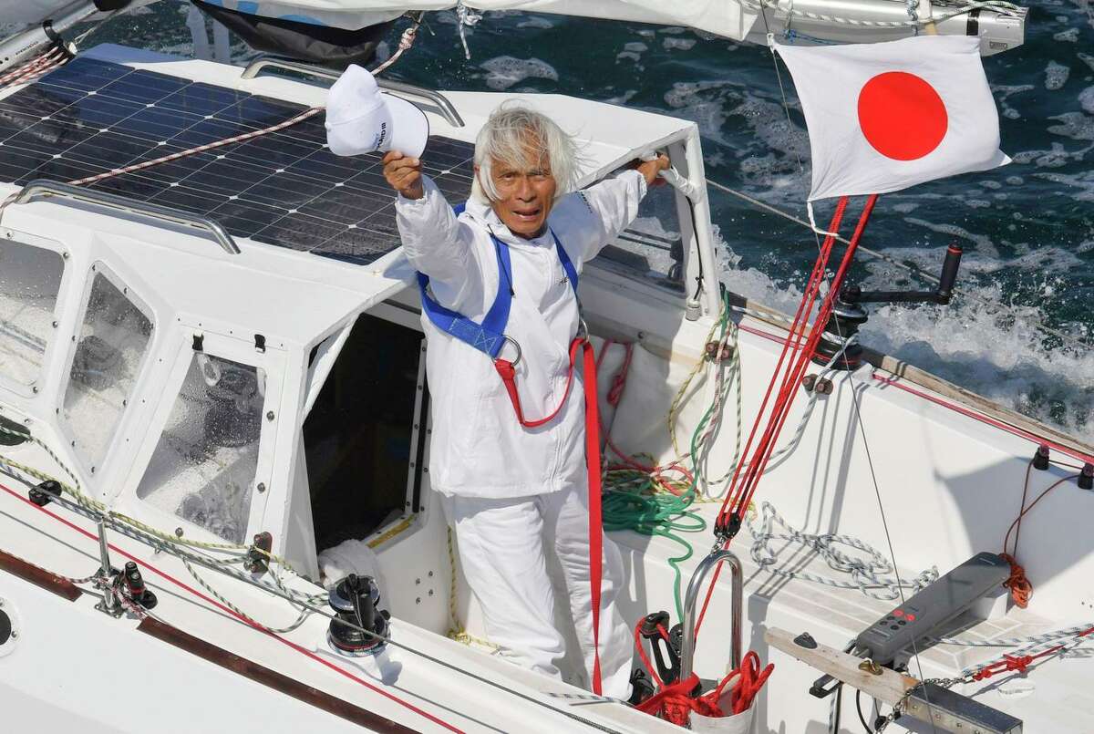 83-year-old Kenichi Horie waves from his boat after his trans-Pacific voyage at Osaka Bay on Saturday.