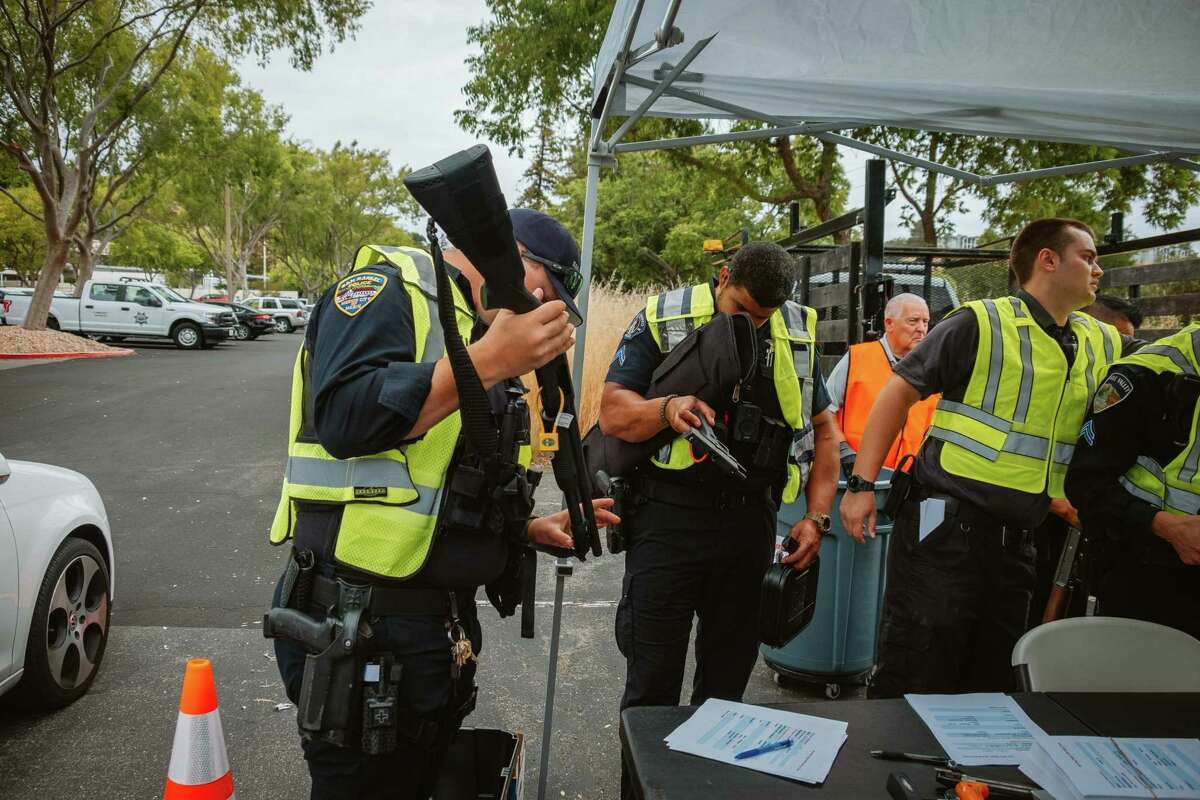 Officers with Central Marin Police check for serial numbers on guns at the anonymous gun buyback program at the Marin County Sheriff’s Office.