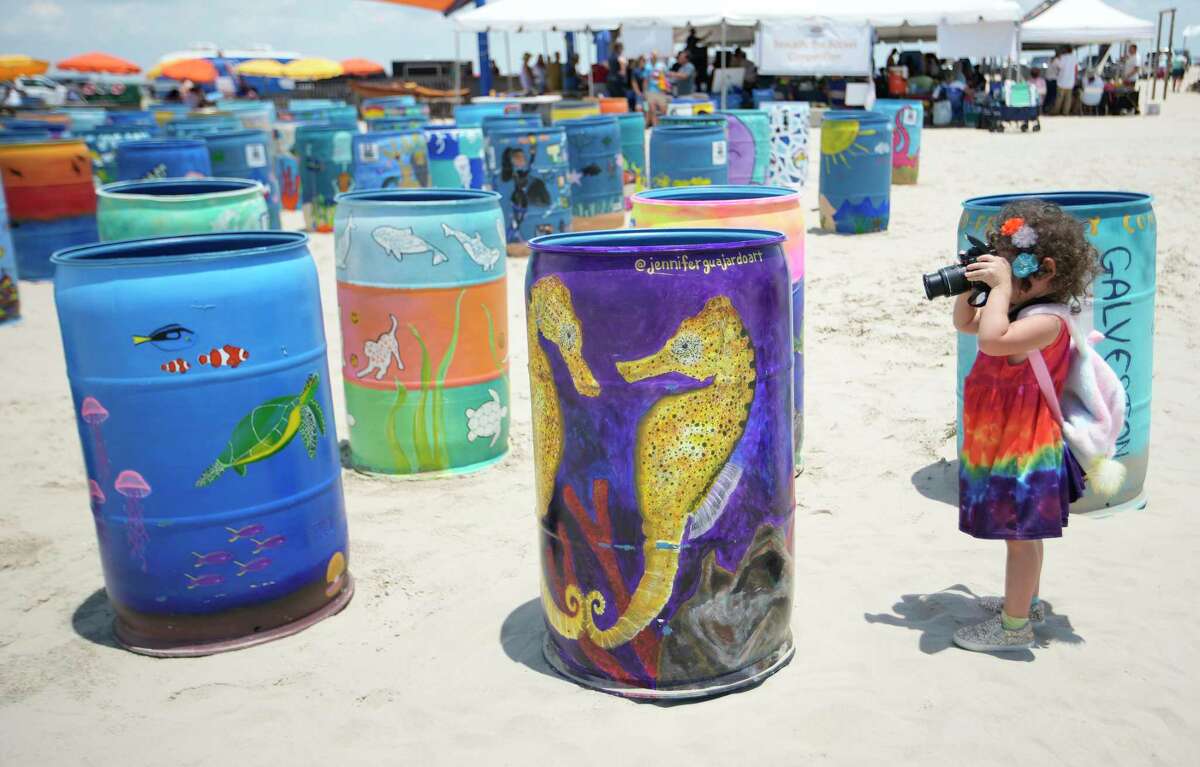 Athena Guajardo, 3, takes photos of mom Jennifer Guajardo’s barrel at Saturday’s World Ocean Day Festival in Galveston.