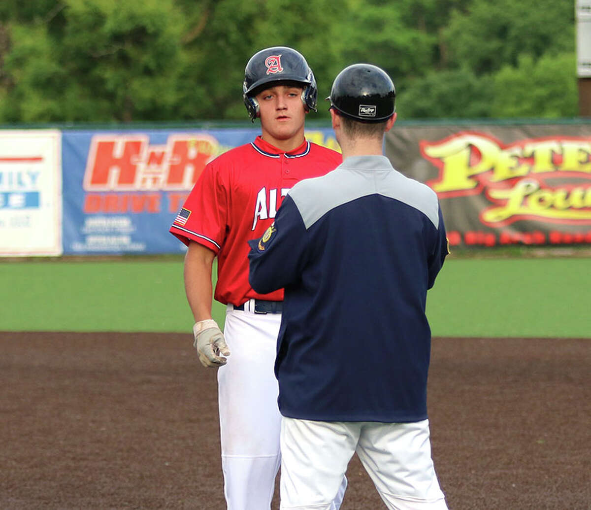 Alton Legion's Tyler Robinson (left) looks to assistant coach Chris Ford after Robinson's single against Maryland Heights on Saturday night at Hopkins Field in Alton.