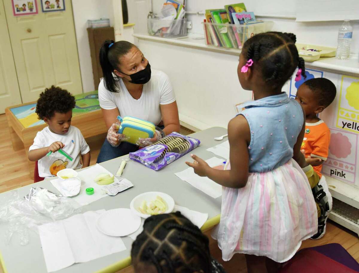 Head teacher Ché Tobin works with students at Children's Playhouse childcare center in Norwalk, Conn. Monday, May 23, 2022. Many childcare centers throughout the region and state are having trouble finding staff.