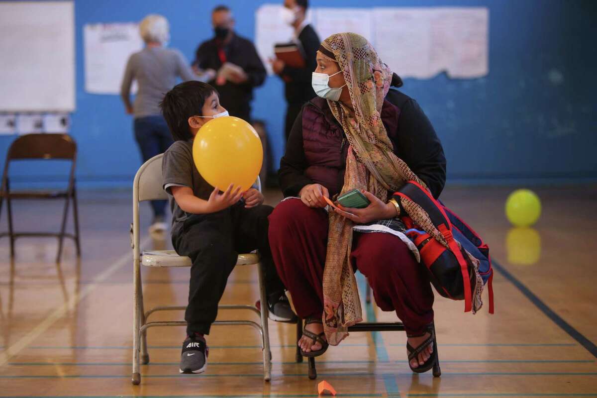 (From left to right) Mustafa Hakim, age 5, and his guardian Samena Rahim wait 15 minutes after Hakim receives his vaccine shot on Friday, March 4, 2022, in San Francisco, Calif.