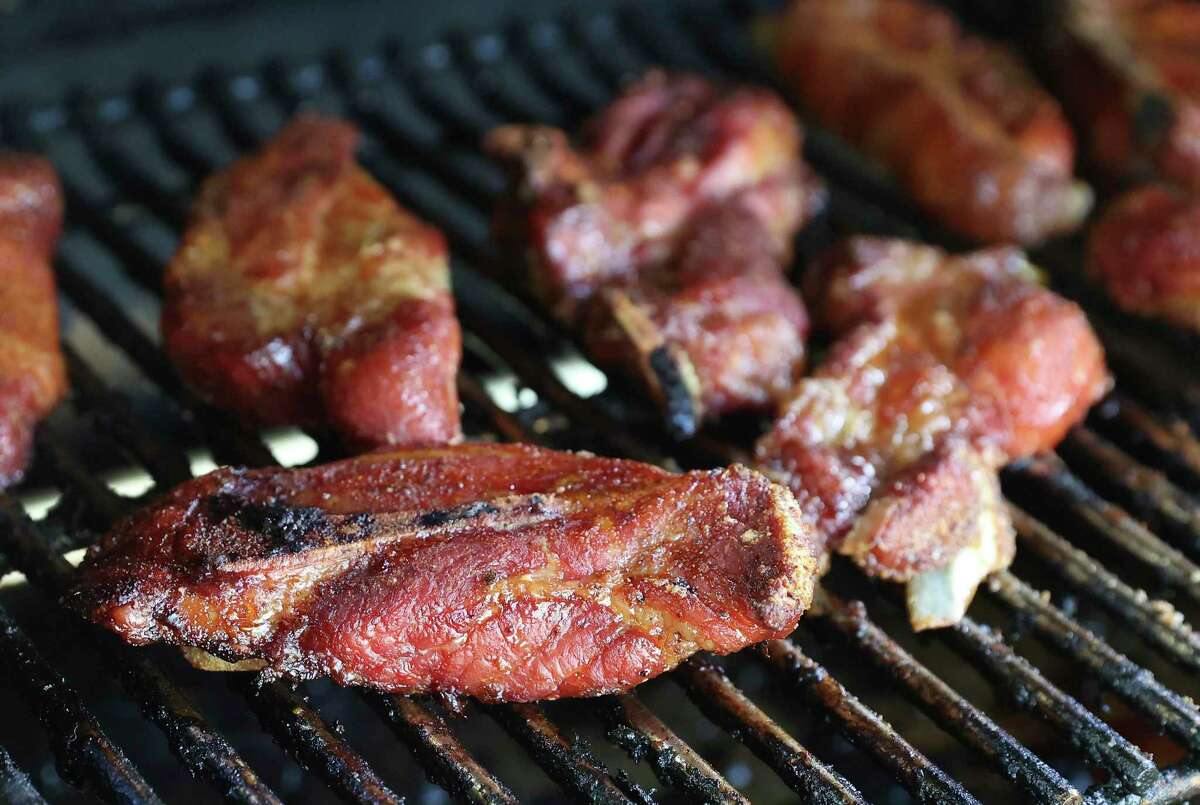 Country-style pork ribs sit in the smoker loaded with cherry wood.