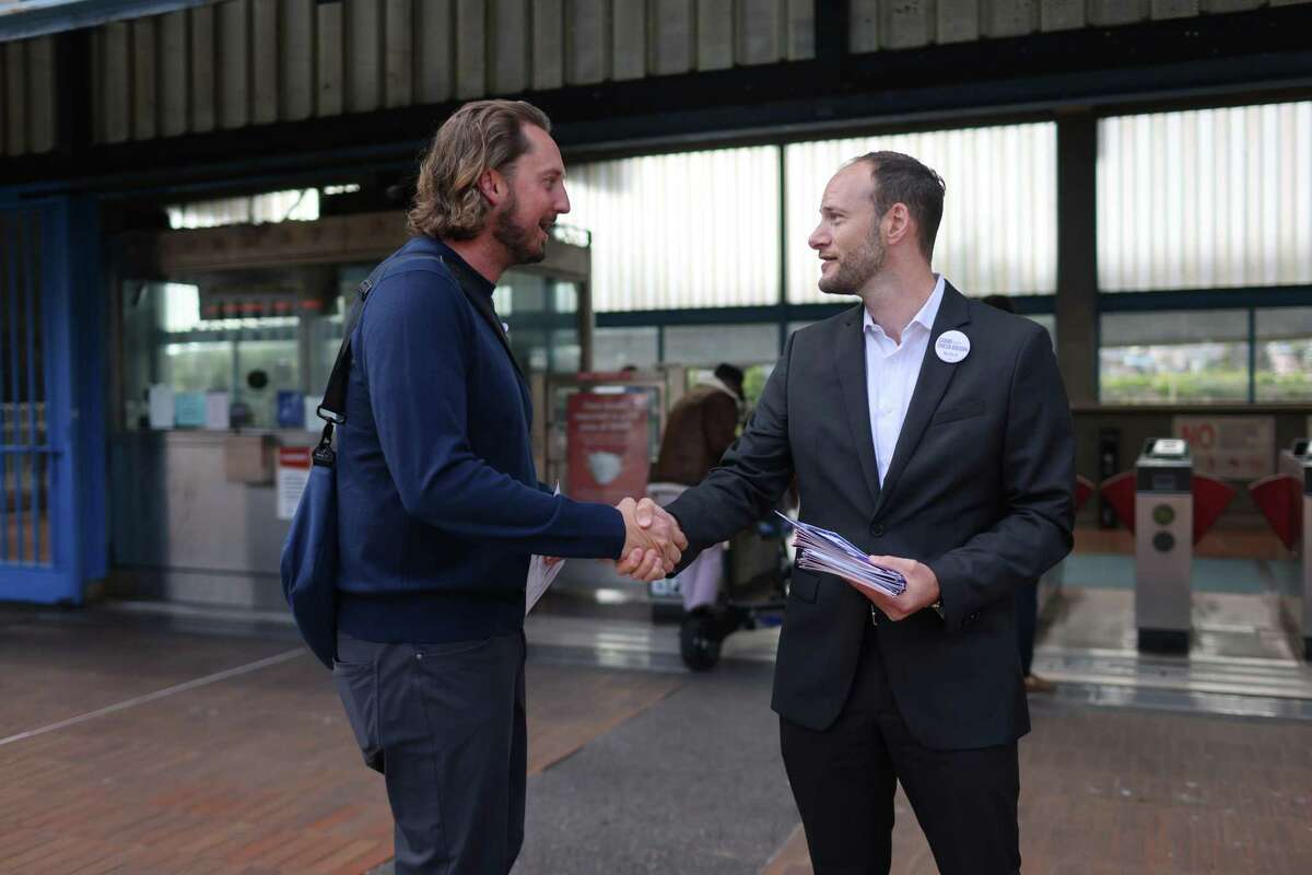 District Attorney Chesa Boudin (right) meets with people ahead of the recall vote at Glen Park BART Station in San Francisco, including Zack Turner.