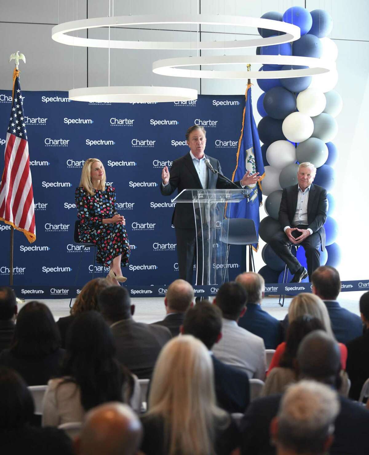 Connecticut Gov. Ned Lamont speaks at the podium beside Stamford Mayor Caroline Simmons and Charter Communications Chairman and CEO Tom Rutledge during the ribbon-cutting at the Charter Communications corporate headquarters in Stamford, Conn. Monday, June 6, 2022. Connecticut Gov. Ned Lamont and Stamford Mayor Caroline Simmons joined Charter leadership to cut the ribbon on the second building of the new Charter headquarters. Building 1, which opened in March 2021, covers about 532,000 square feet across 14 floors, Building 2 encompasses about 288,000 square feet across nine floors, and the three-story connecting structure contains about 94,000 square feet.
