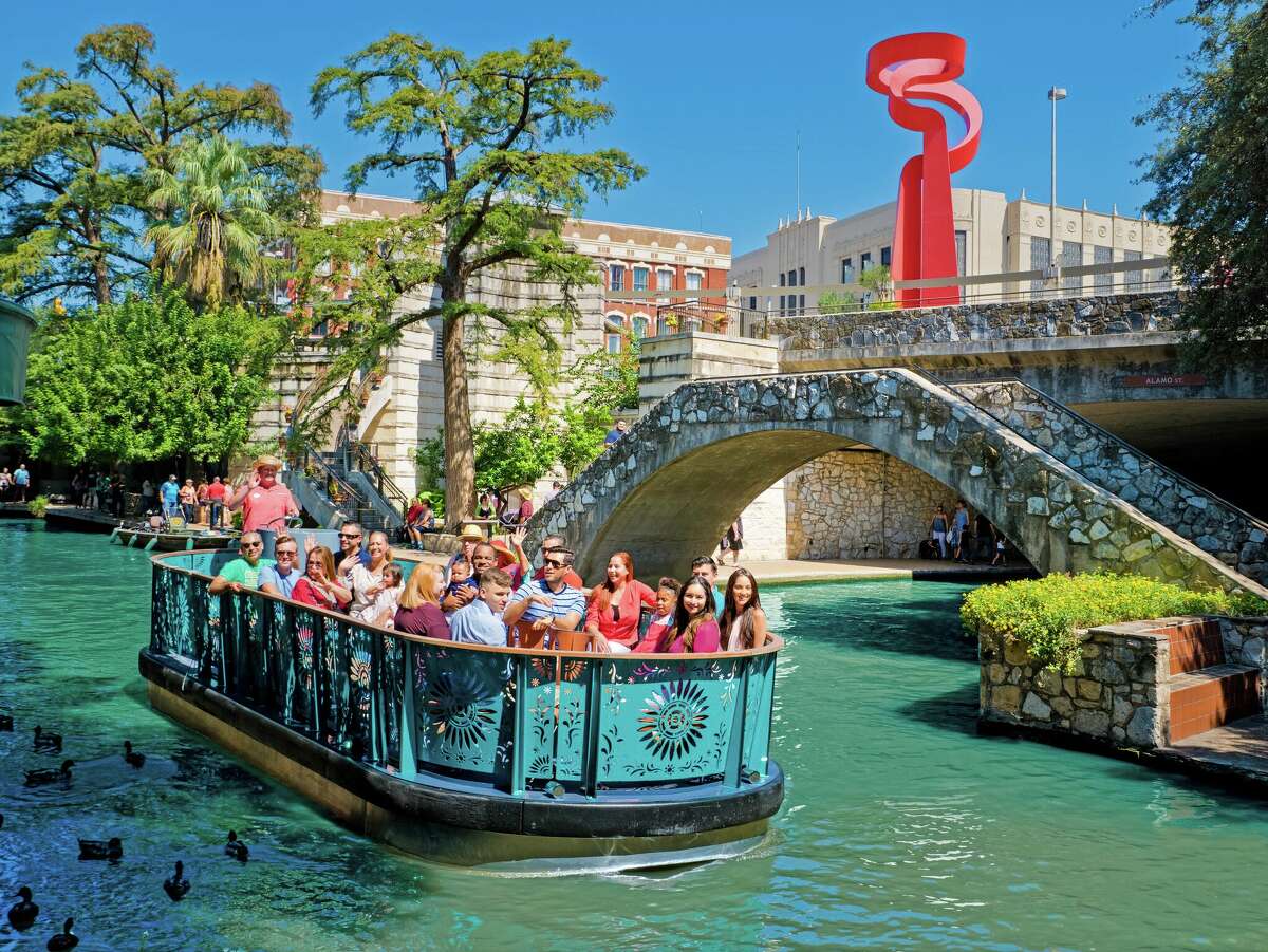 Passengers enjoy a tour of the River Walk aboard a blue barge electric boat run by Go Rio Cruises. 